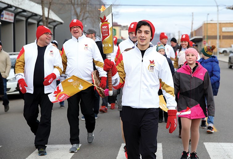 Local skater Justin Hampole carries the torch back towards Canada Games Plaza during the final leg of the MNP Canada Winter Games Torch Relay on Saturday morning.