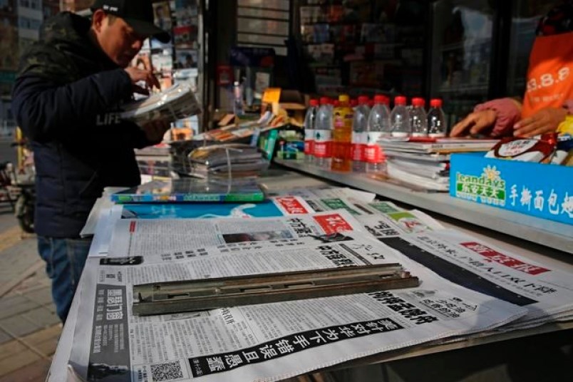 A man arranges magazines near newspapers with the headlines of China outcry against U.S. on the detention of Huawei's chief financial officer, Meng Wanzhou, at a news stand in Beijing, Monday, Dec. 10, 2018. China has summoned the U.S. ambassador to Beijing to protest Canada's detention of an executive of Chinese electronics giant Huawei at Washington's behest and demand the U.S. cancel an order for her arrest. (AP Photo/Andy Wong)