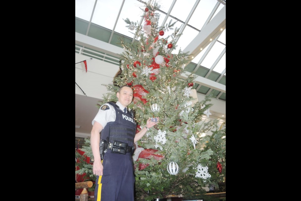 Richmond RCMP's Cpl. Dennis Hwang shows off the 21-foot fir tree, which was donated to the detachment with some very special meaning. Alan Campbell photo
