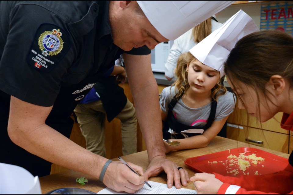 The Hot Flying Eagle Chefs, including special Const. Sheldon Frayle, Grade 4 F.W. Howay student Sienna Stewardson, centre, and Grade 5 Qayqayt student Adriana Meikle work on their recipe at the Cooking with Cops event held last week.