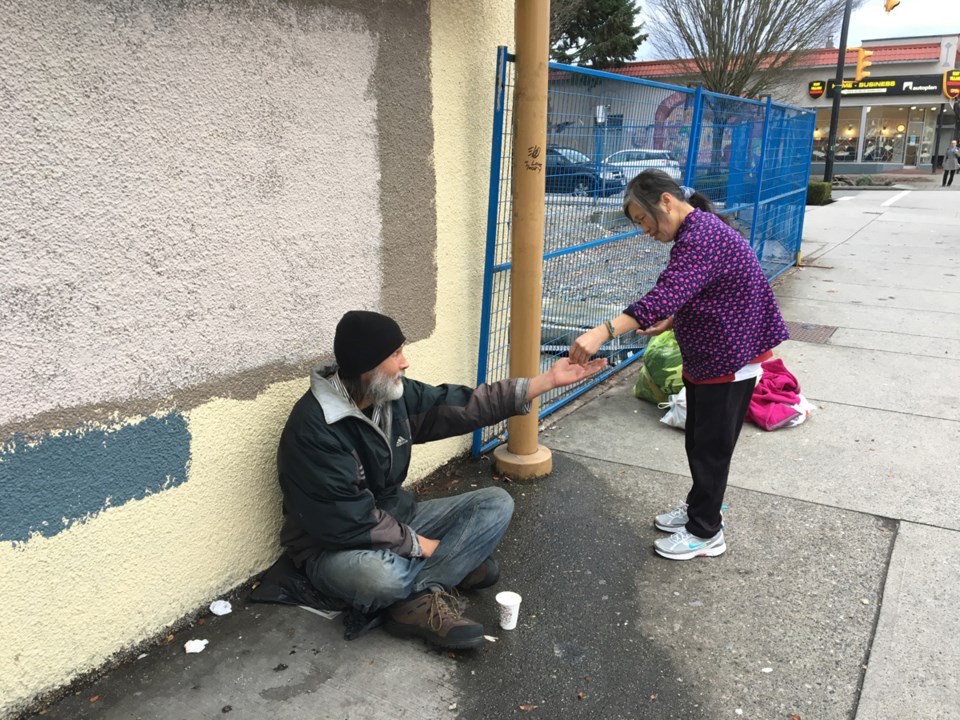 Gia Tran stops and gives some money to a person asking for change. Photo Grant Lawrence