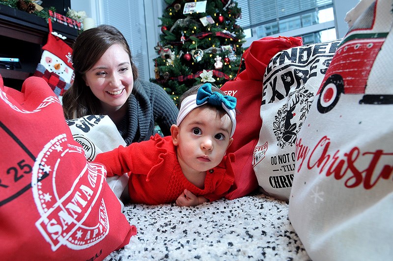 One year-old Ella Arruda gets a close-up look at some of the Christmas sacks her mom, Jenna Whitehead Arruda, and other families who had premature babies in the Neonatal Intensive Care Unit at Royal Columbian Hospital last Christmas have put together for families in a similar situation at the hospital this year.