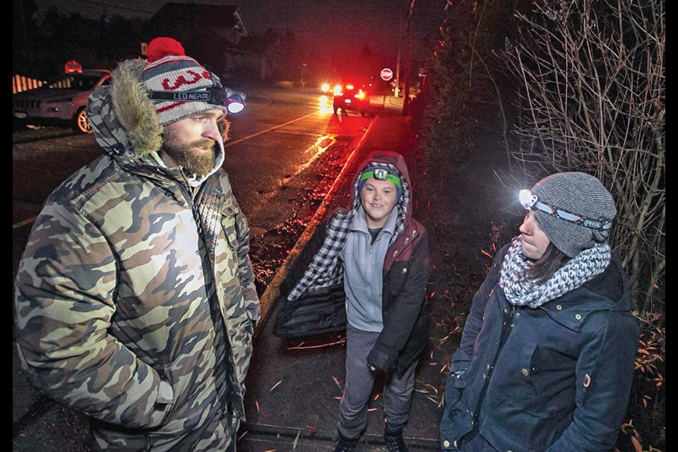 Jason Glutek, left, his son, Kohen, and Steph Fulcher use headlamps to navigate Willow Street in Chemainus.