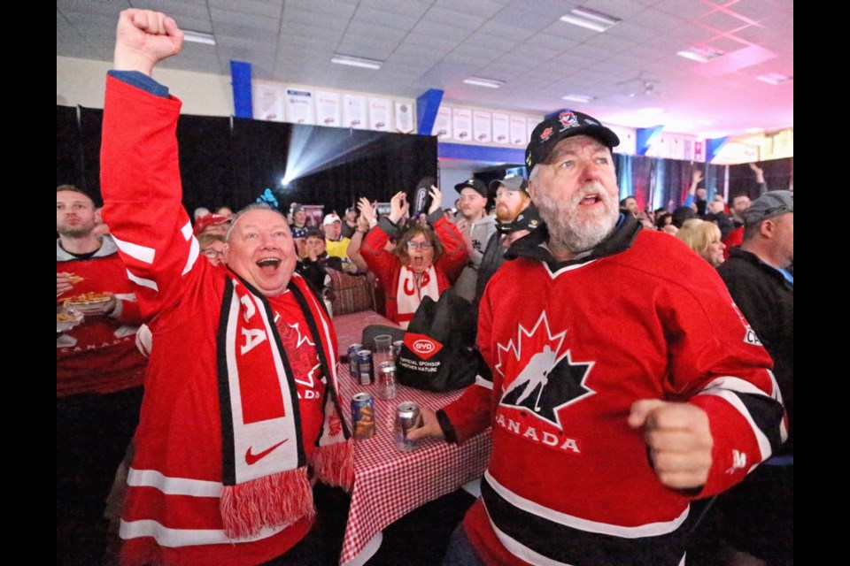 Darren Gover, left, and Wayne Salmon celebrate a Team Canada goal with the hundreds of fans watching the game at the Cabin near Save-on-Foods Memorial Centre on Thursday. Dec. 27, 2018