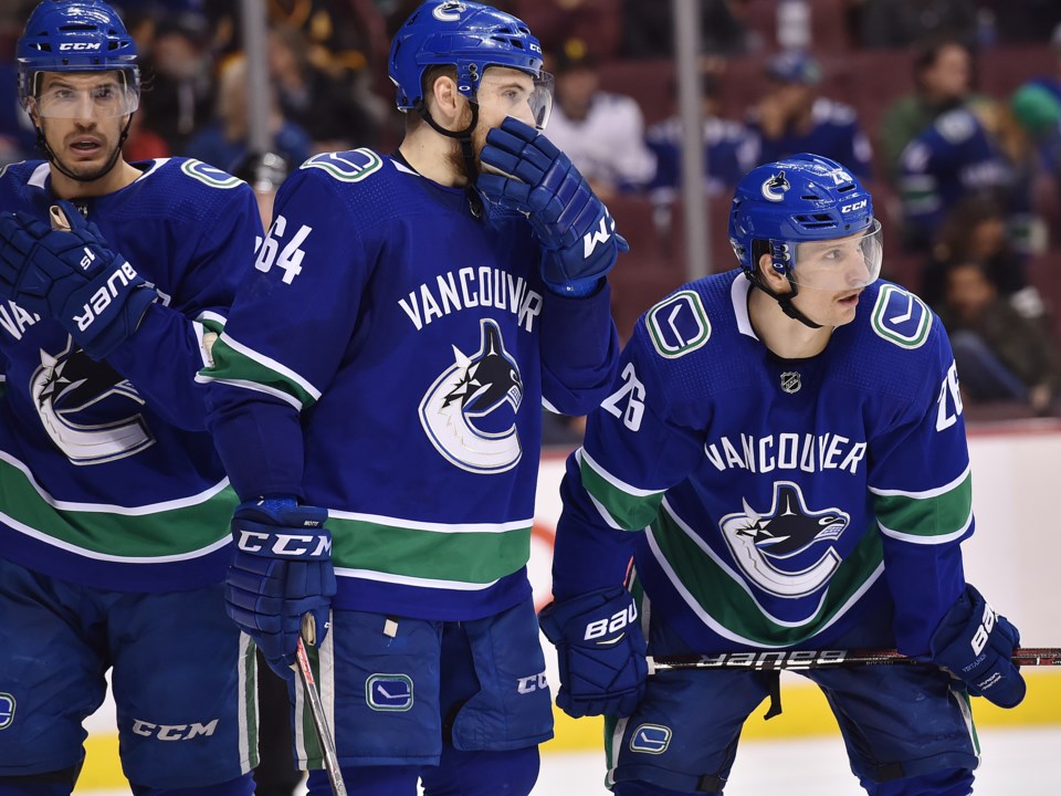 Michael Del Zotto, Tyler Motte, and Antoine Roussel wait for the puck to be dropped.