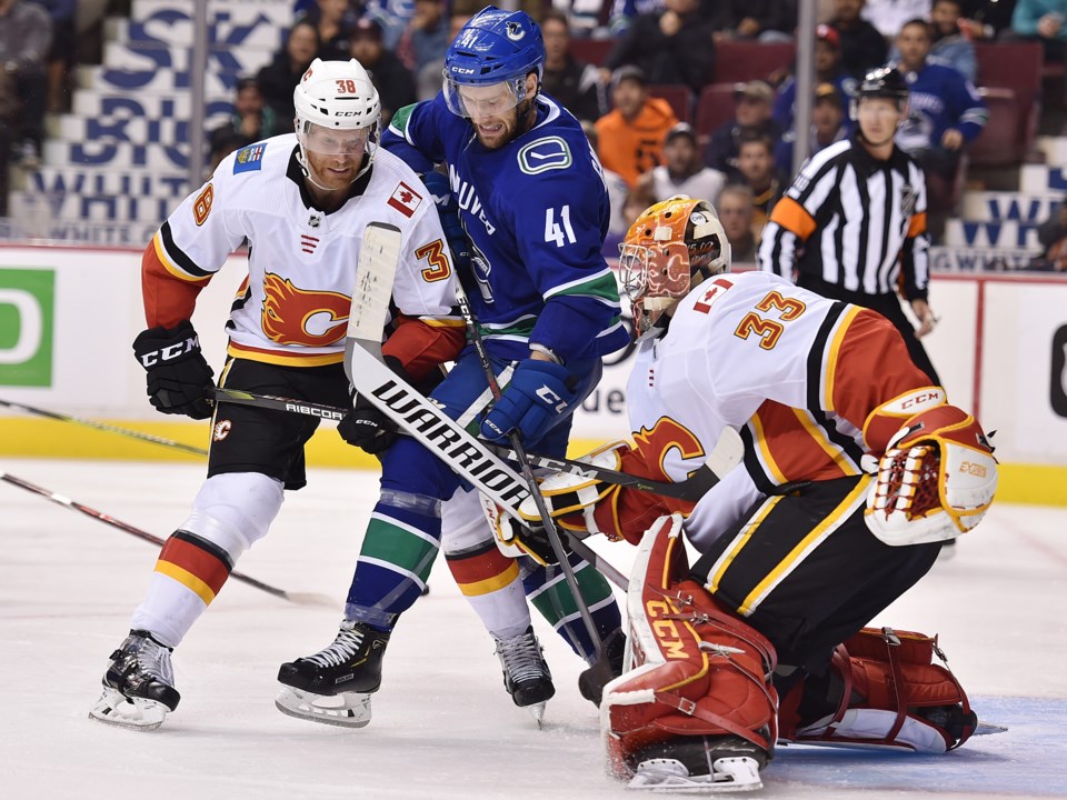 Jonah Gadjovich battles in front of the Calgary Flames net for the Vancouver Canucks.
