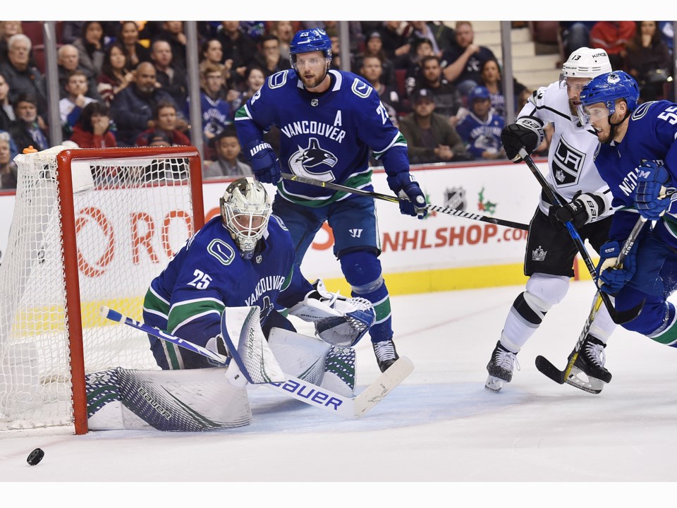 Jacob Markstrom makes a save while Alex Edler and Alex Biega chase down the rebound.