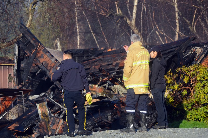 RCMP and fire investigators look over an abandoned Byrne Road house destroyed by fire Monday night.