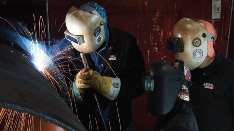 Instructor Bernard Booth welds as students Scott Haig and Corinne Hagen observe at United Associatio