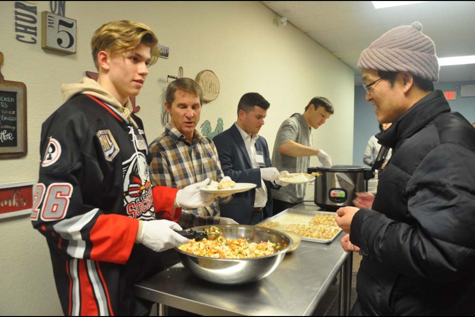 A volunteer from Richmond Sockeye, the city's Junior B hockey team, is serving food to people at a community dinner that takes place every Wednesday night at Church on Five. Daisy Xiong photo
