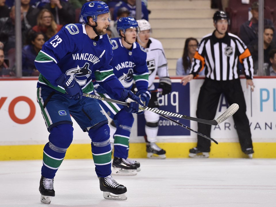 Alex Edler watches the puck as Elias Pettersson skates in the background for the Vancouver Canucks.