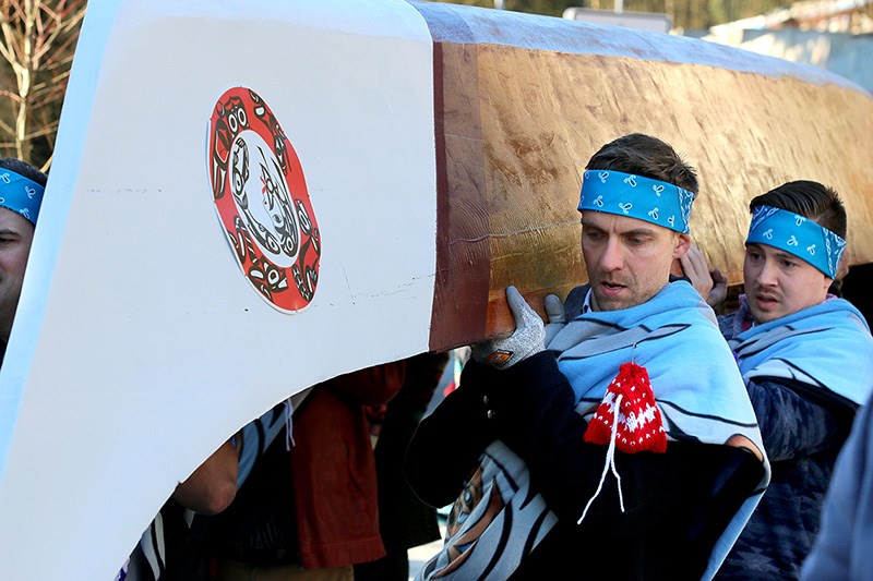 MARIO BARTEL/THE TRI-CITY NEWS The canoe, carved from a single log, is a handful for more than a dozen volunteers carrying it.