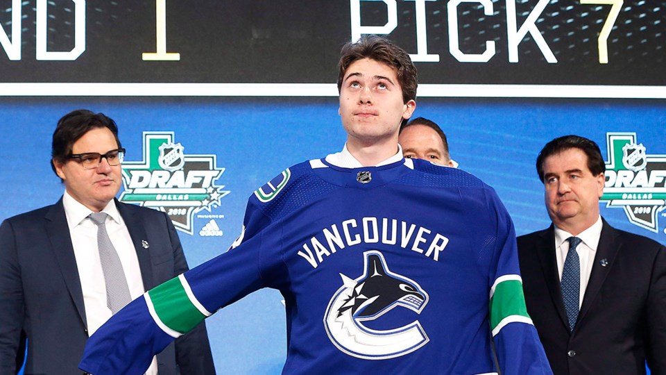 Quinn Hughes puts on a Canucks jersey at the 2018 NHL All-Star Draft.