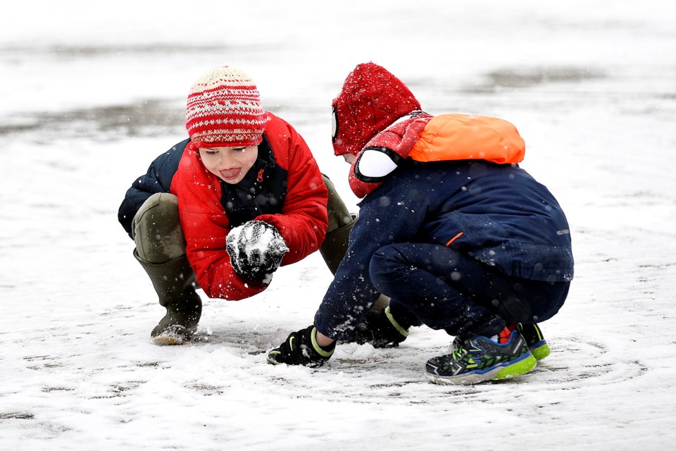 Rafe Salmond and Freddie Gretton play in the snow on the boardwalk outside of the River Market.