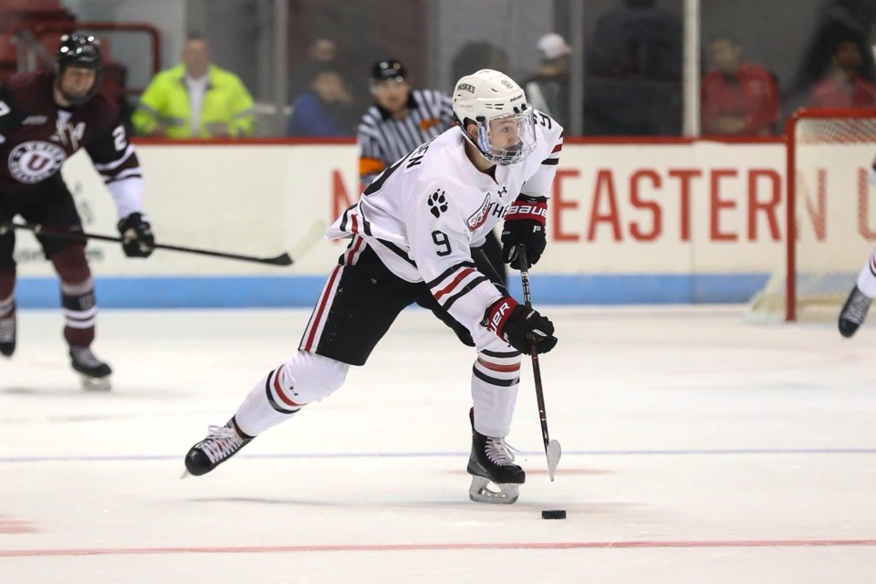 Tyler Madden carries the puck up ice for the Northeastern University Huskies.