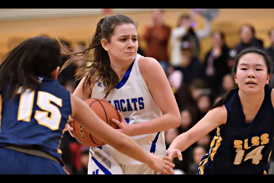 McMath's Jayna Wilson heads to the basket between Steveston-London's Shir Dayan (left) and Mina Chong during Thursday's Richmond Senior Girls Basketball championship game at Burnett. The Wildcats won their sixth straight city title with a 77-58 victory.