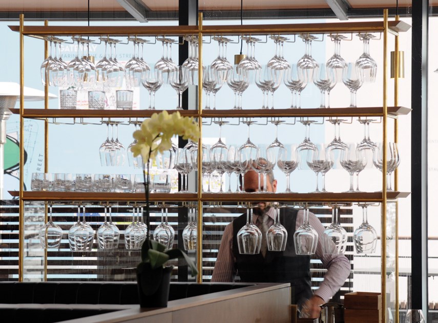 The design of Ancora Ambleside in the Grosvenor building on the West Vancouver waterfront is elegant and modern, featuring a bustling open kitchen with bar-style seating, massive windows and a high, ornate ceiling.