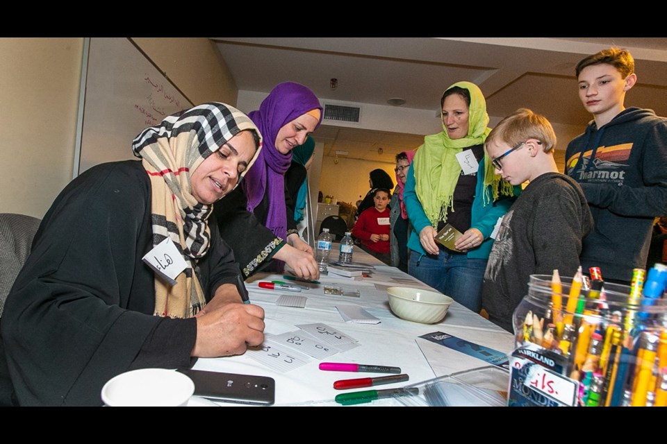 Hana Alqadafi writes names in Arabic for visitors to the open house at Masjid Al-Iman mosque on Saturday.