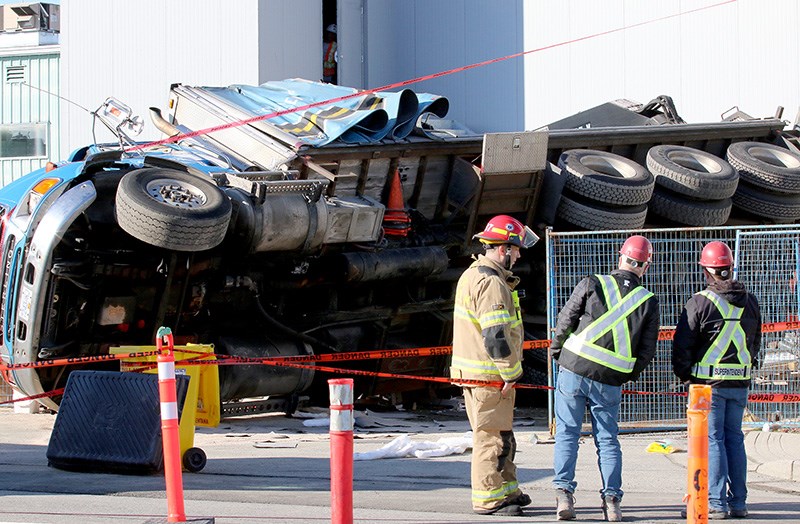 A Port Coquitlam firefighter talks with workers at the new PoCo Rec Complex after a crane delivery truck tipped over on Friday morning.