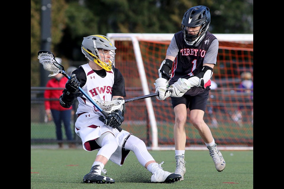 MARIO BARTEL/THE TRI-CITY NEWS Heritage Woods Kodiaks forward Josh Coupal stumbles to the ground as he's checked by Terry Fox Ravens defender Aiden Graham in the first quarter of their senior Tier 2 game at the BC provincial high school field lacrosse championships, being held at Town Centre Park in Coquitlam all week.