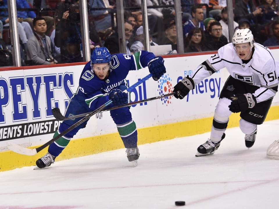 Troy Stecher passes the puck from behind the Vancouver Canucks net.