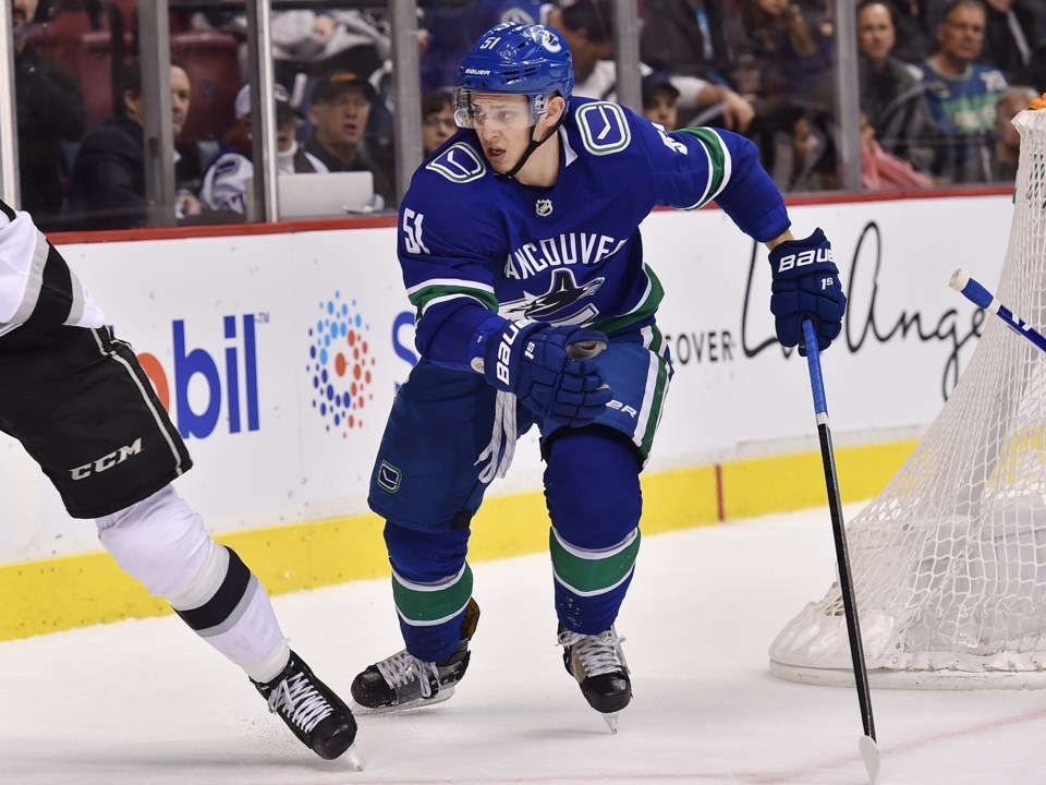 Troy Stecher tracks his check behind the net for the Vancouver Canucks.