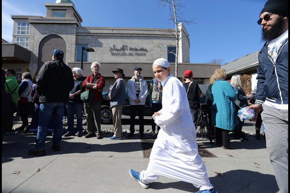 Omar Jammal walks past a human chain around the Al-Iman mosque on Friday.