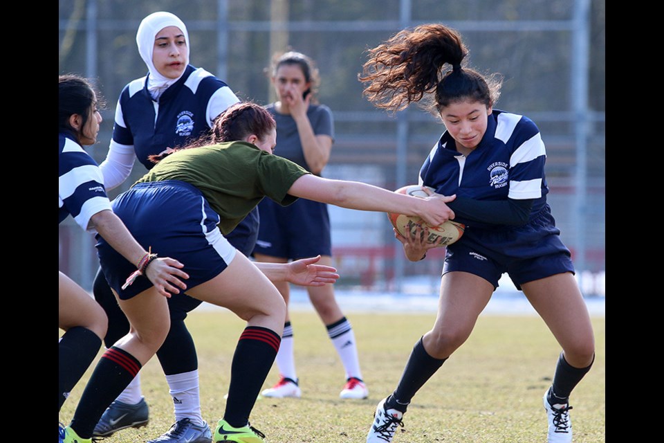 The Riverside Rapids girls development rugby team works on tackling drills during a recent pre-season practice.