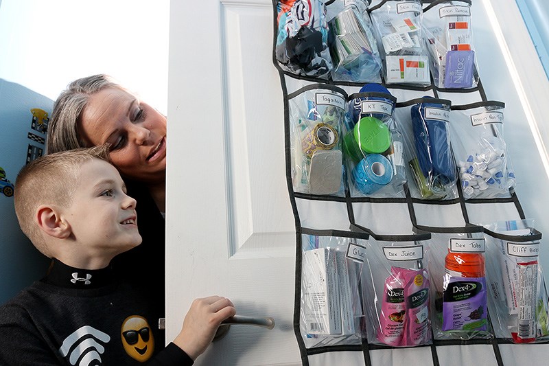 Nicholas Legge and his mom, Cindy, check out the organizer for his daily diabetes supplies he has hanging on his bedroom door.
