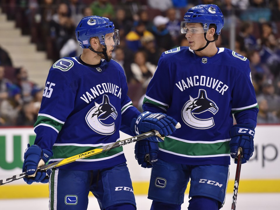 Alex Biega and Jake Virtanen talk before a faceoff for the Canucks.