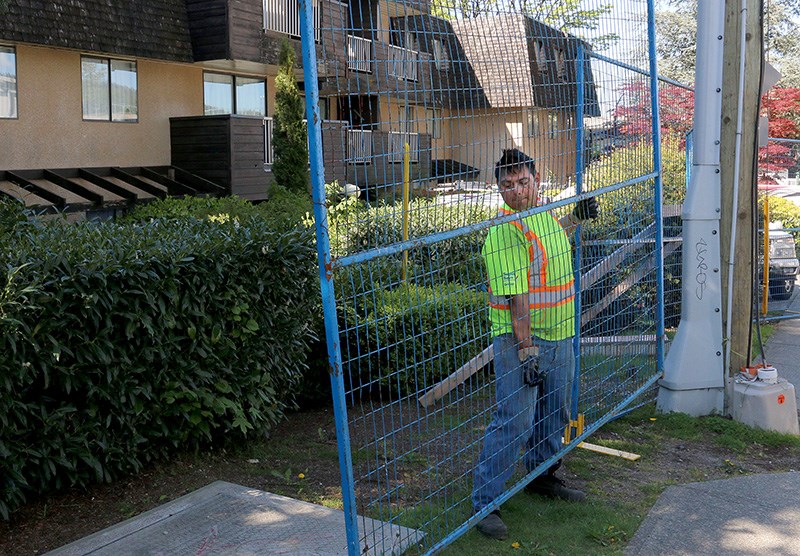 A worker installs fencing around a Coquitlam apartment building at North Road and Foster Avenue where a fire early Tuesday morning forced residents from their homes.
