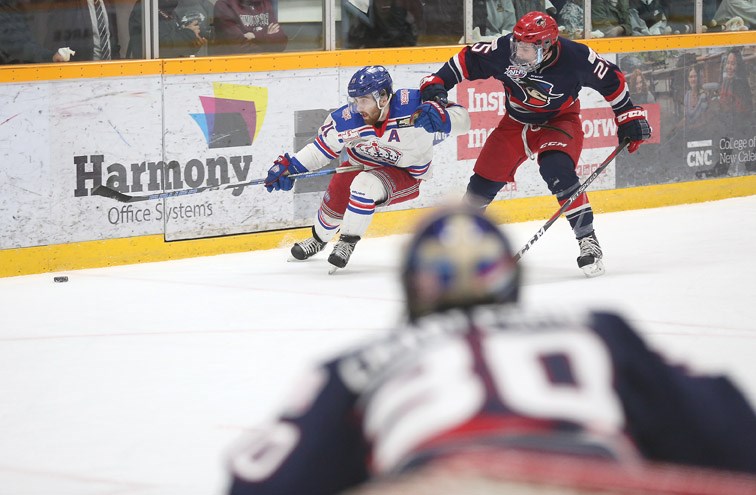 Prince George Spruce Kings forward Patrick Cozzi chases the loose puck while being held up by Brooks Bandits defender Orca Wiesblatt on Wednesday evening at Rolling Mix Concrete Arena in the fourth game of the best-of-seven Doyle Cup series.