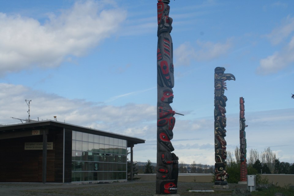 Three totem poles stand in front of the Aboriginal Gathering Place at Vancouver Island University.