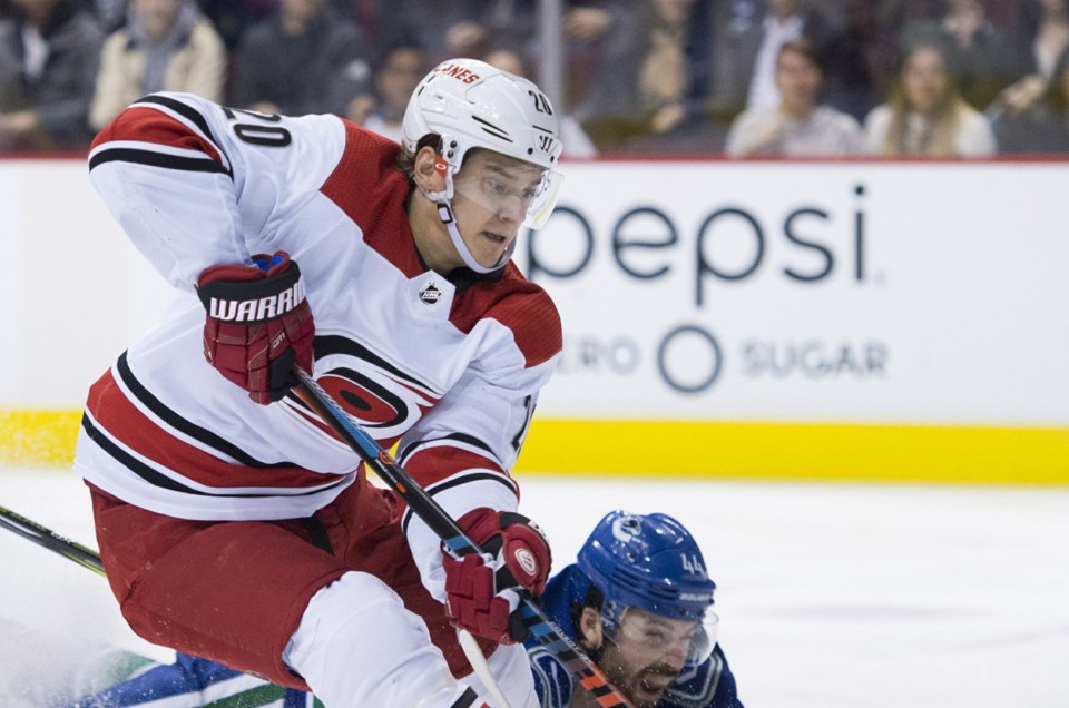 The Carolina Hurricanes' Sebastian Aho carries the puck past a diving Erik Gudbranson.