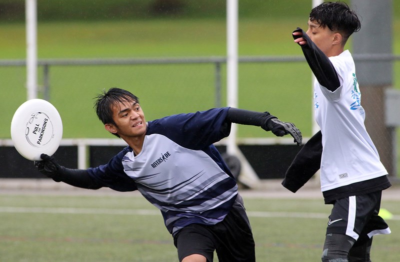 MARIO BARTEL/THE TRI-CITY NEWS Riverside's Jhun Earnes Suniega looks for a receiver around a St. Thomas More defender in a recent high school Ultimate match at Gates Park in Port Coquitlam. The league has been growing in popularity and was sanctioned last year as an official activity by BC School Sports.