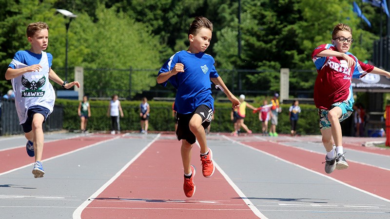 MARIO BARTEL/THE TRI-CITY NEWS Competitors in a boys 100m race leap for the finish line.