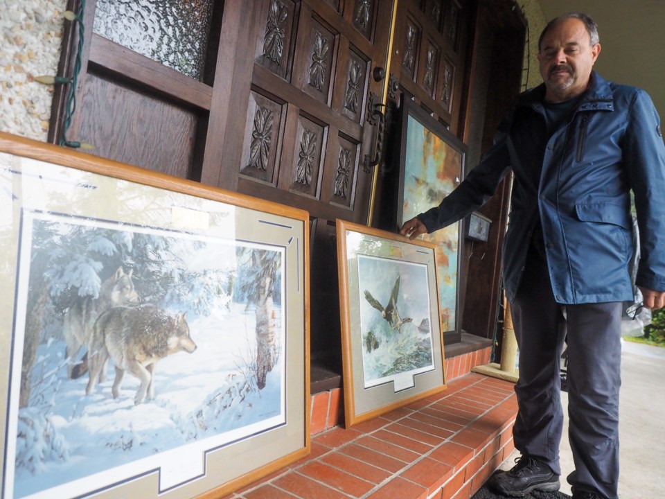 Nick Dominelli shows off his set of Periss Clayton Weirs paintings kept safe from the rain under the