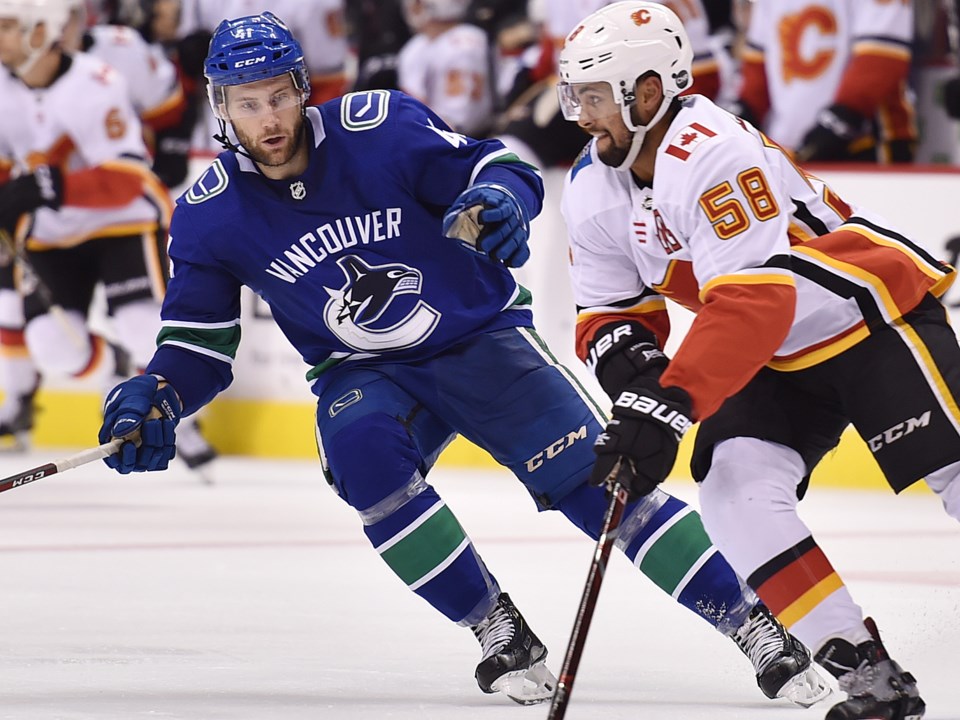 Jonah Gadjovich keeps an eye on a Calgary Flames player during the 2018 preseason.