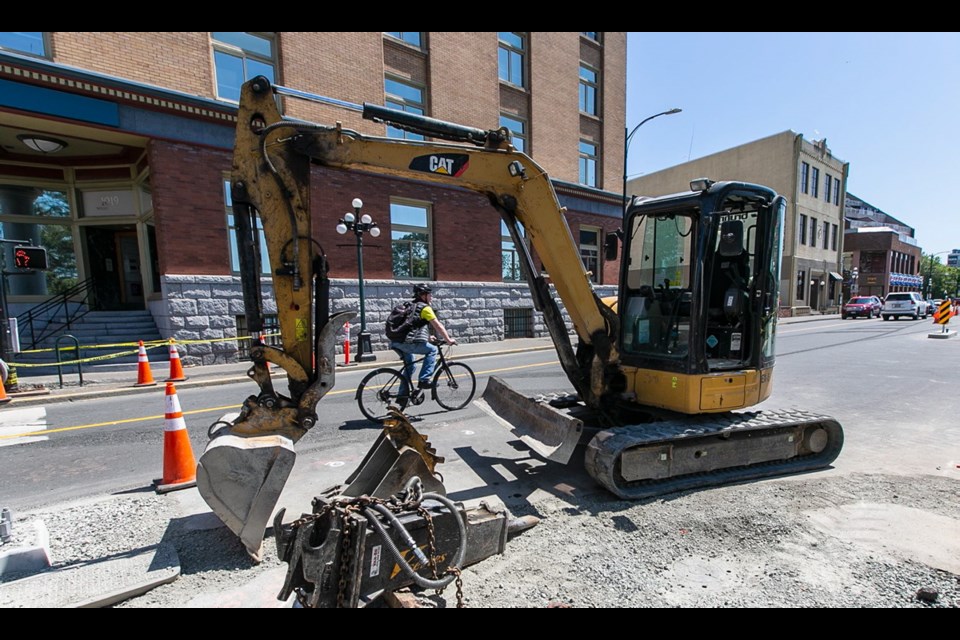 A cyclist rides past bike-lane construction on Wharf Street, near Fort Street.