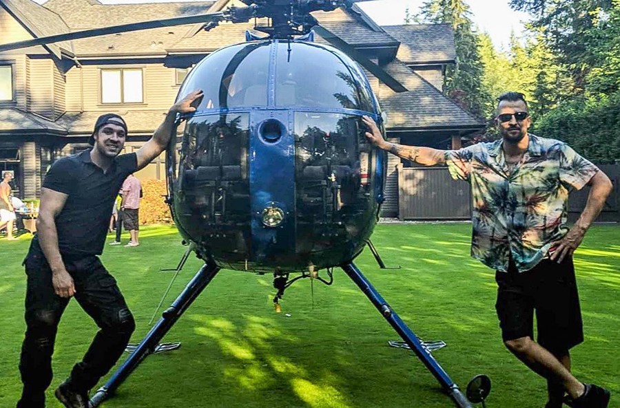 Justin Plosz, right, next to a helicopter that landed in the backyard of his Anmore home.