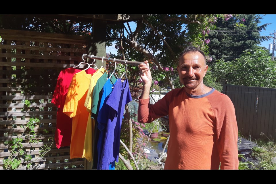 Fraser Biggs displays his makeshift pride flag – which he fashioned out of T-shirts after someone took the flag from his second-floor apartment in Gibsons.