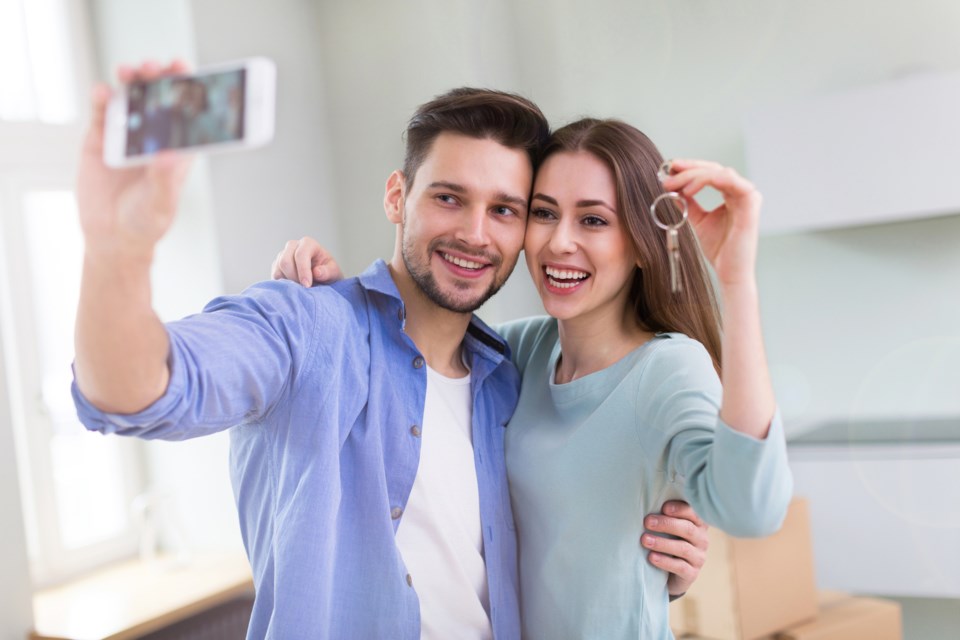 Young couple first-time buyers keys selfie home