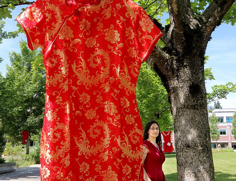 Douglas College instructor Teresa Howell stands amidst some of the 24 red dresses hung in trees on the Coquitlam campus by students in her third year psychology class to help raise awareness around the issue of murdered and missing Indigenous women and girls.