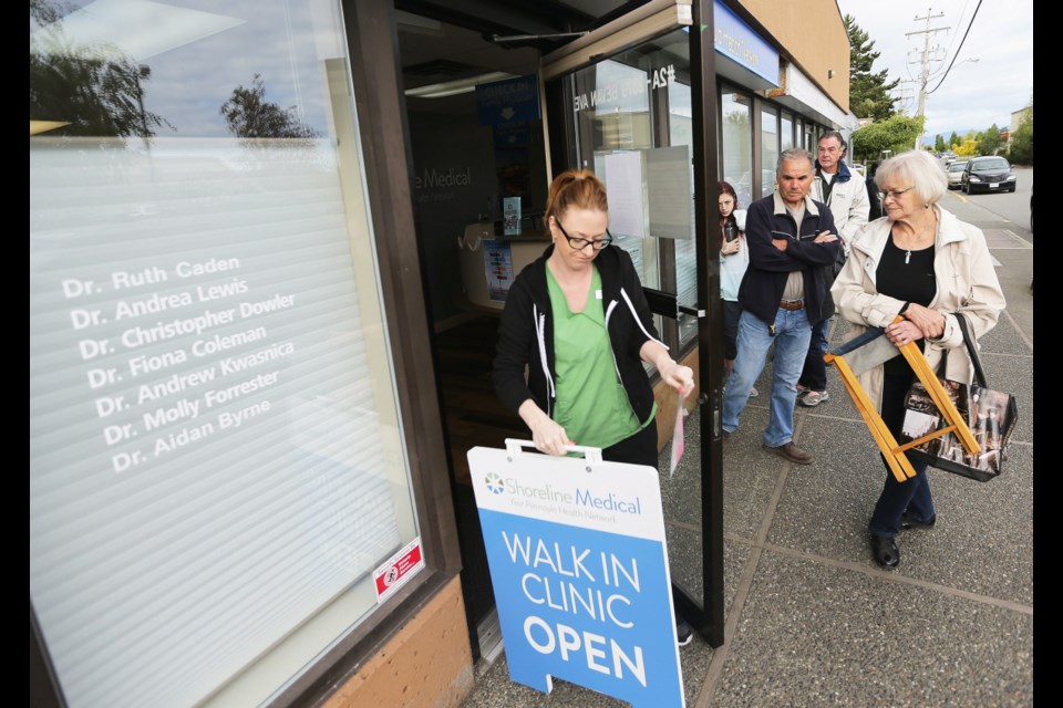 Medical office assistant Andrea Pecho, left, opens the door for Susan McConnell, right, who had been waiting more than an hour before the 8:30 a.m. opening time at Sidney&rsquo;s Shoreline Medical on Bevan Avenue.