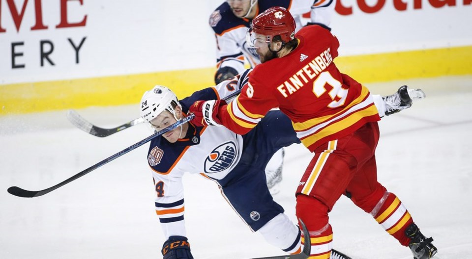 The Calgary Flames' Oscar Fantenberg checks the Edmonton Oilers' Brad Malone.