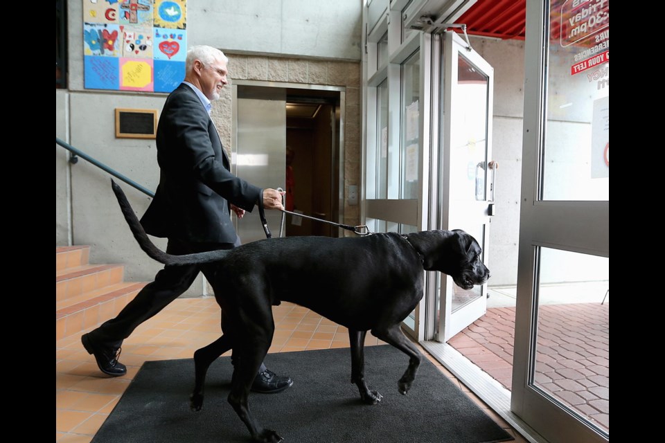 RCMP Sgt. John Ferguson and Lewis, his five-year-old Great Dane, walk out of the West Shore RCMP detachment on Wednesday. Ferguson was walking his dog while off-duty when he recognized the two escapers after one of them said: &Ograve;What a big dog.&Oacute; July 10, 2019