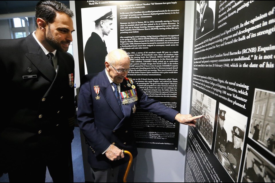 Base Commander Capt. (N) Sam Sader, left, and veteran sailor Commander Peter Chance look at a photo of Ted Simmons, part of an exhibit for the war hero at CFB Esquimalt Naval and Military Museum.