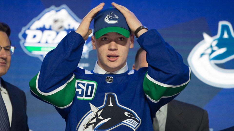 Vasili Podkolzin dons a Canucks hat at the 2019 NHL Entry Draft in Vancouver.