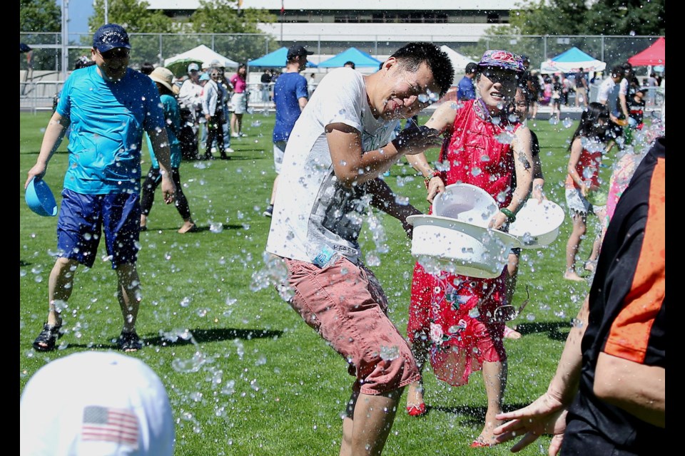 People pour water over each other at the Water Splashing Festival at the Burnaby's Swangard Stadium.