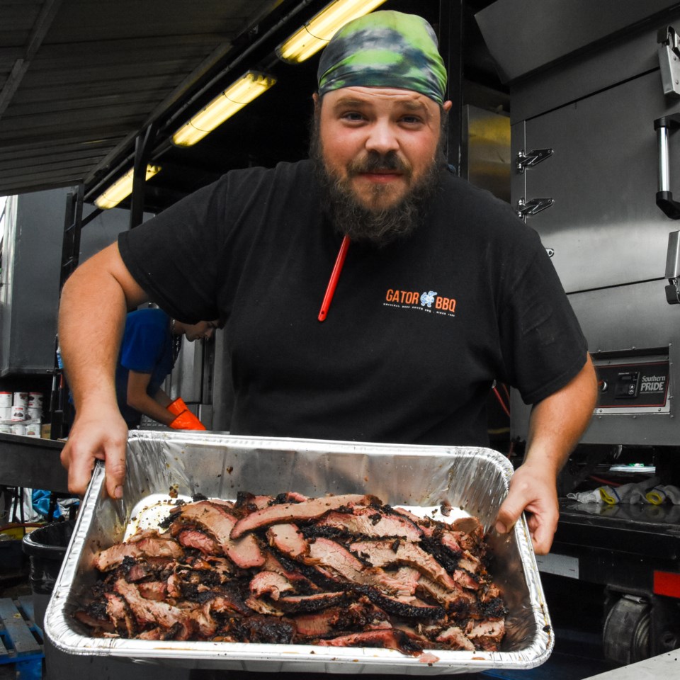 Nick Smith shows off freshly sliced beef brisket behind the Gator BBQ rig at Port Moody's RibFest